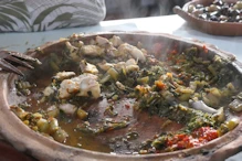 Sea food and spinach cooked over a fire eaten with a wooden fork