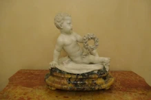 A fine sculpture of a cupid with a wreath