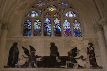 A stained glass window with dark painting below