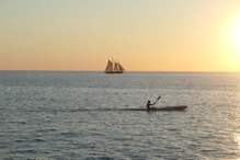 A sailing boat and kayack with golden sky